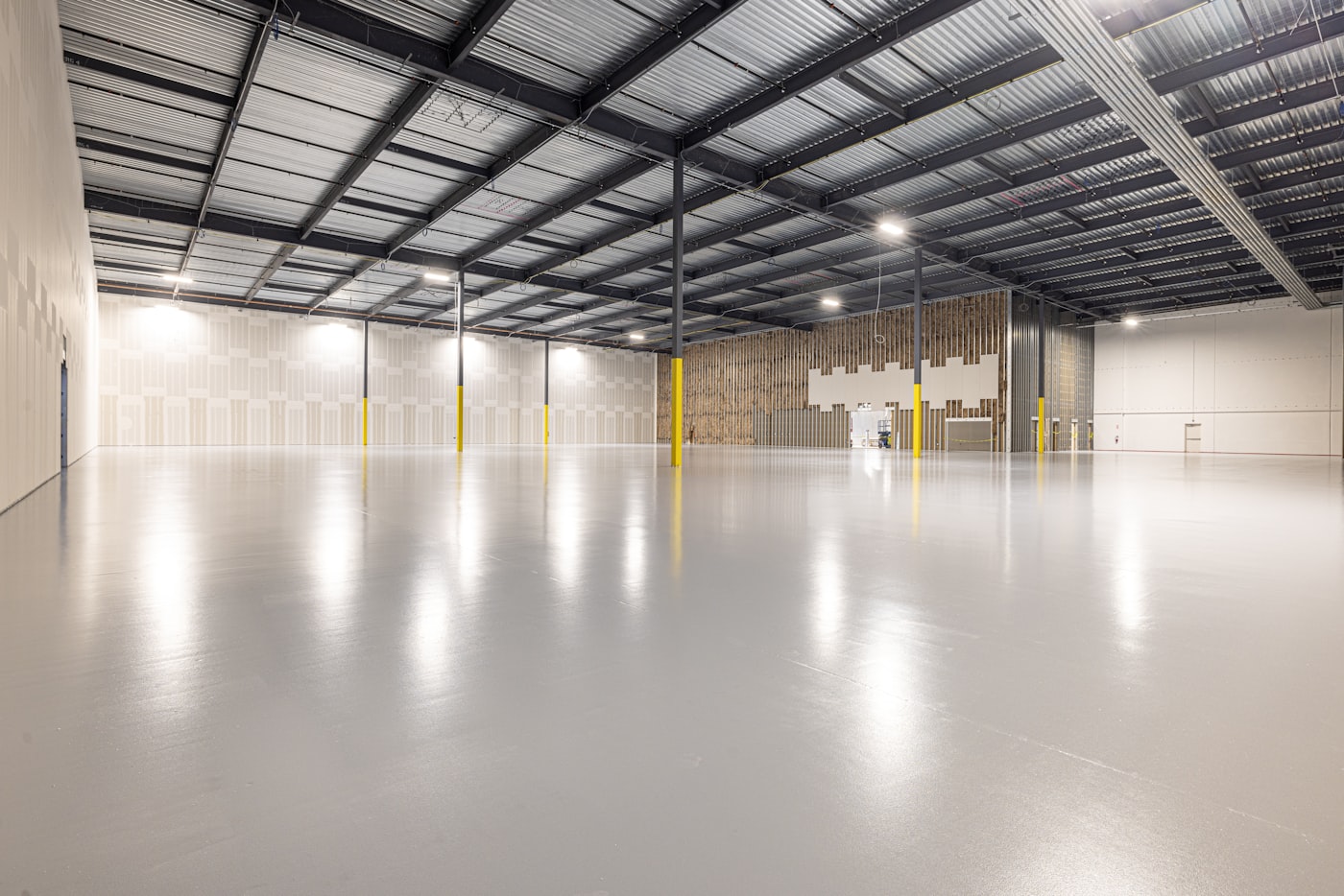A finished polyaspartic floor coating in a bright, empty industrial hall.